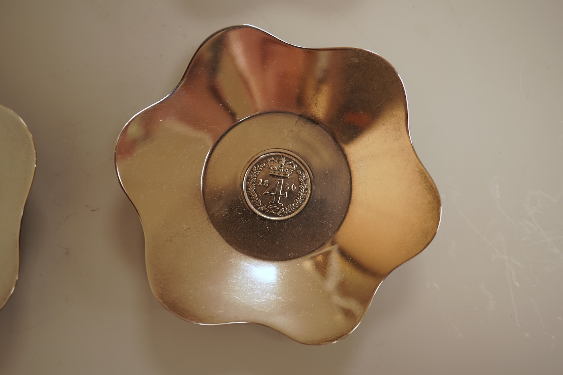 A cased set of four George V silver flower head shaped nut dishes, each inset with an 1850 maundy coin, Walker & Hall, Birmingham, 1936, diameter 77mm.